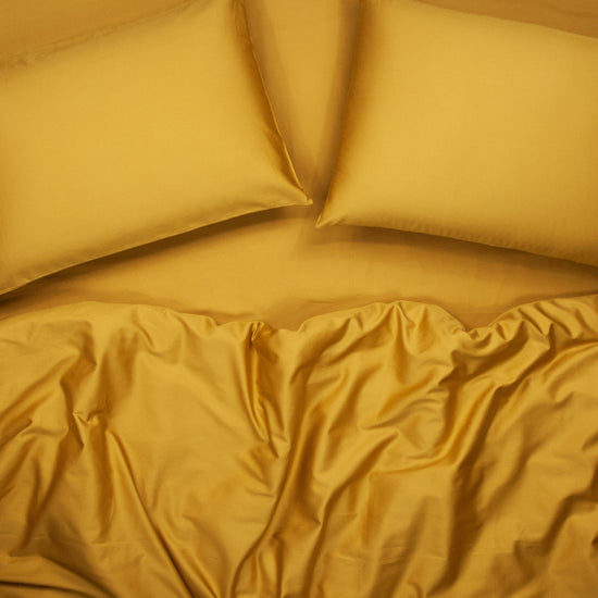 Birds eye view of organic cotton complete bedding set with pillowcases, sheets and quilt cover in honey gold
