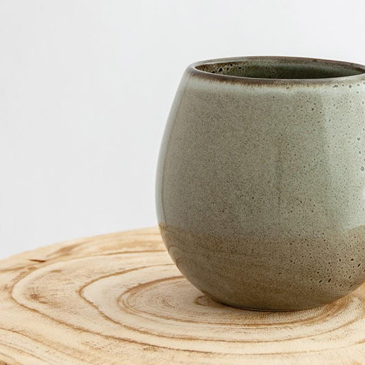 Close up of a Robert Gordon banksia grey canvas mug coffee cup sitting on a natural wooden round side table