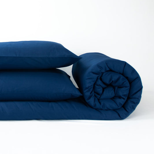 Stack of organic cotton quilt cover set with pillowcases and rolled up quilt cover in classic blue