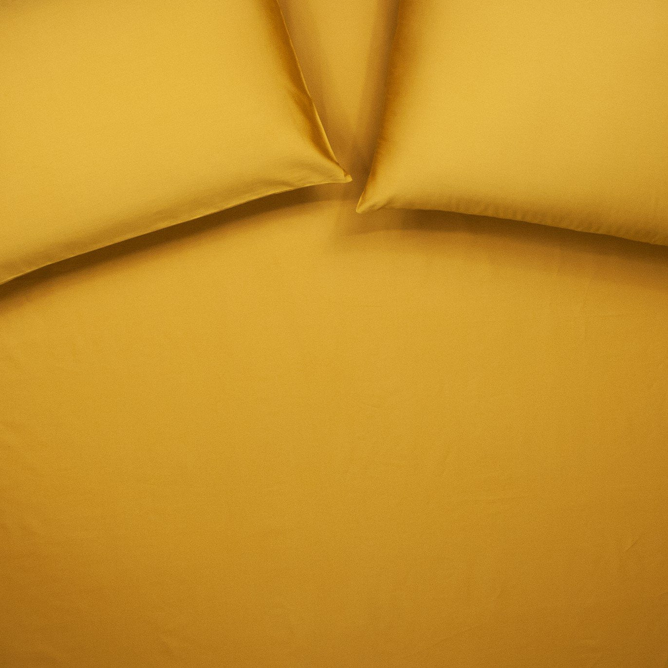 Birds eye view of organic cotton fitted sheet with pillowcases in honey gold