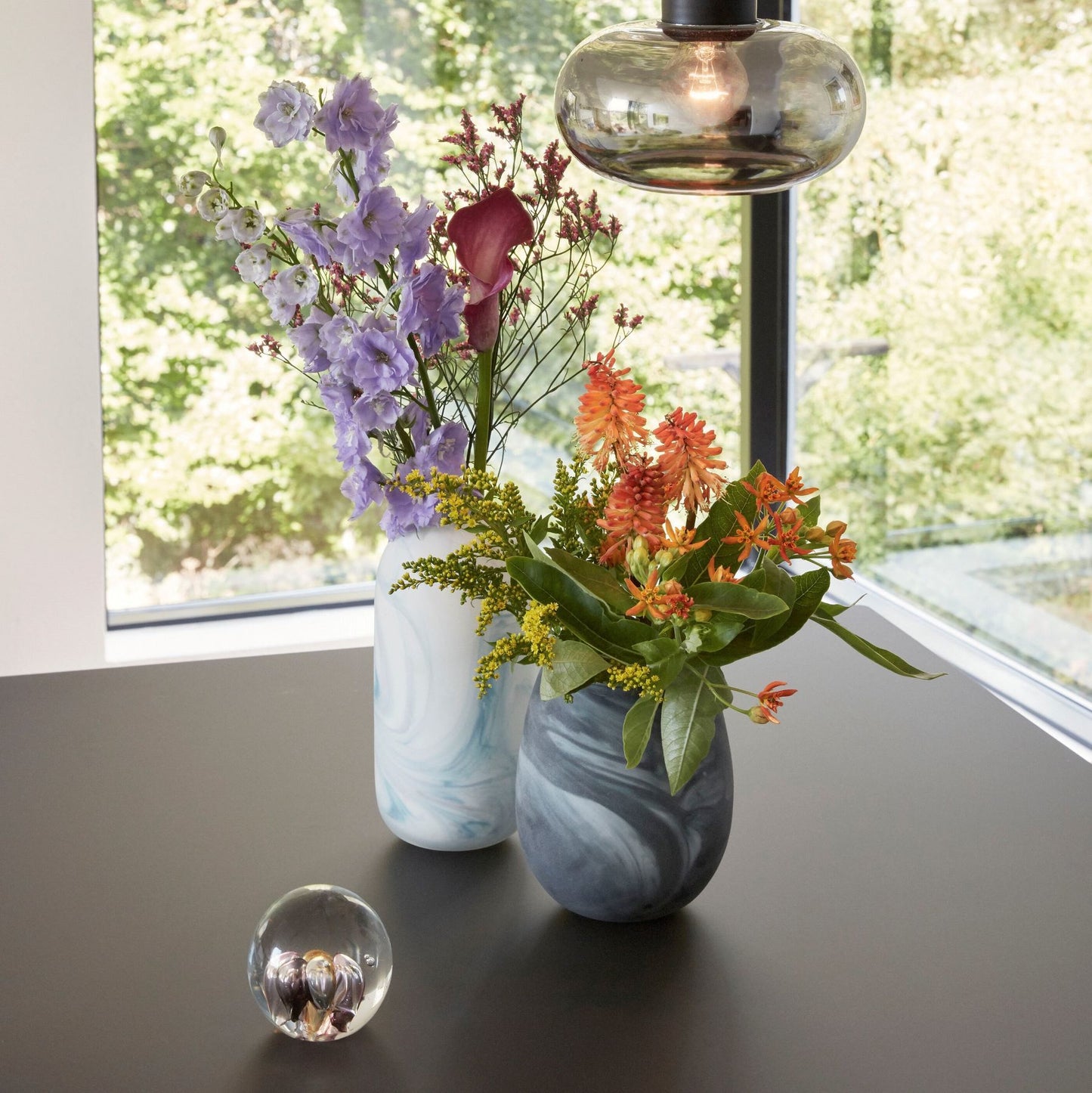 Hubsch Interior Scandi style marbled vases in white and blue glass sitting on black dining table with paperweight