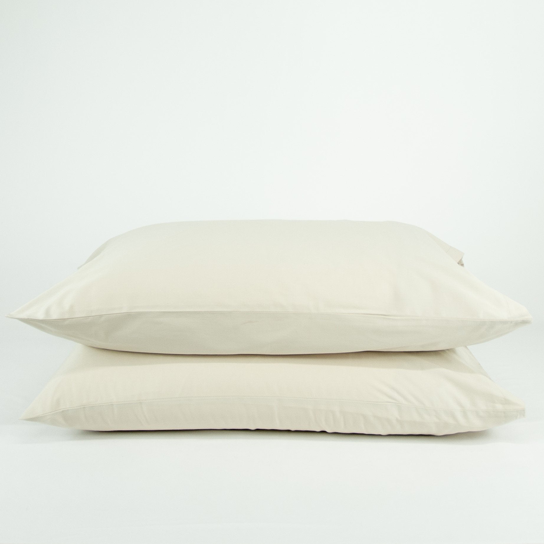 Stacked organic cotton pillowcases in egg shell white