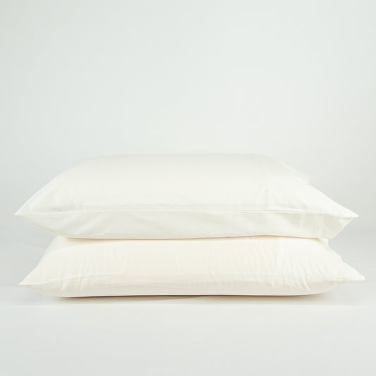 Stacked organic cotton pillowcases in warm white