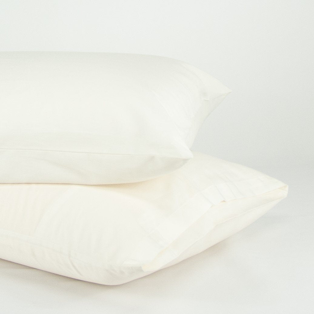 Stacked organic cotton pillowcases in warm white