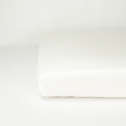End of mattress with organic cotton fitted cot sheet in warm white