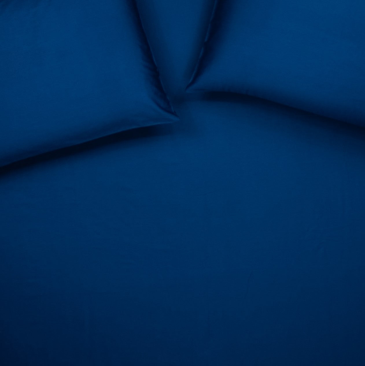 Birds eye view of organic cotton fitted sheet with pillowcases in classic blue