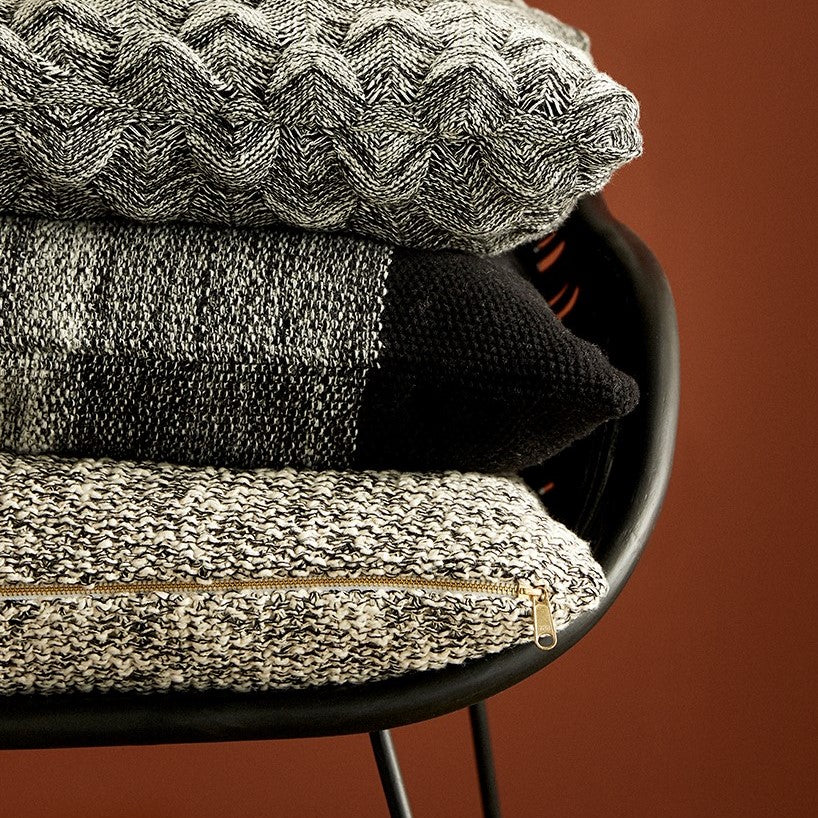 Hubsch Interior Scandi designer throw pillows in a stack on a black rattan chair