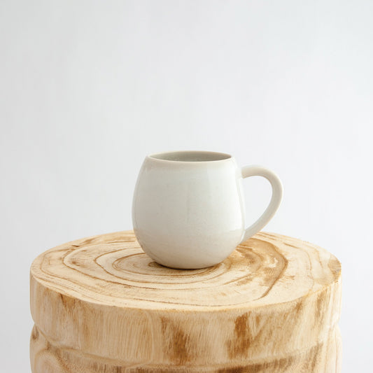 Robert Gordon coast white canvas mug coffee cup sitting on a natural wooden round side table
