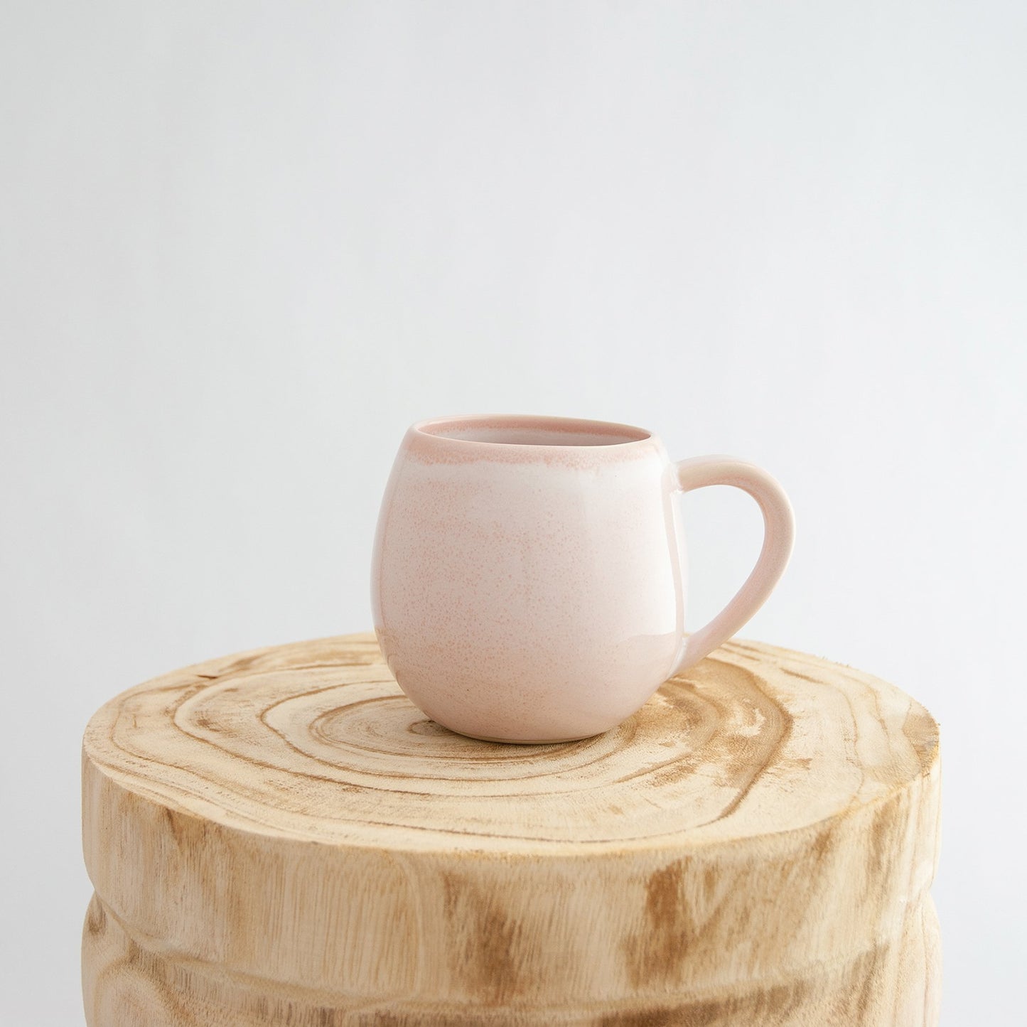 Robert Gordon rose quartz pink canvas mug coffee cup sitting on a natural wooden round side table