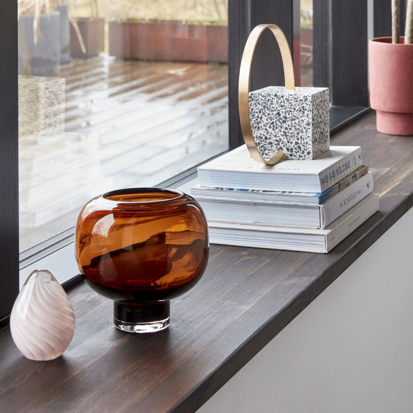 Hubsch Interior Nordic designer fish-bowl style cocoon vase in brown glass sitting inside on a window sill with some books