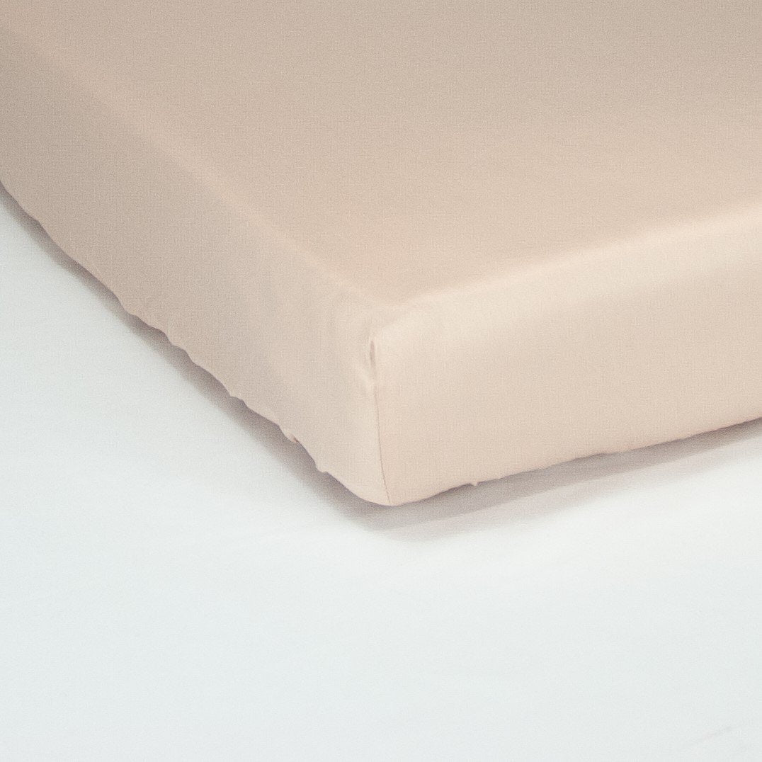Corner of mattress with organic cotton fitted cot sheet in blush pink