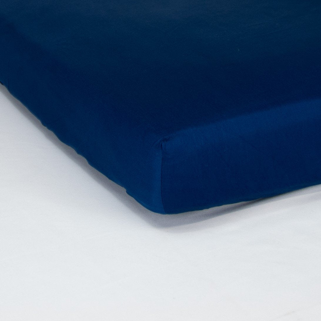 Corner of mattress with organic cotton fitted cot sheet in classic blue