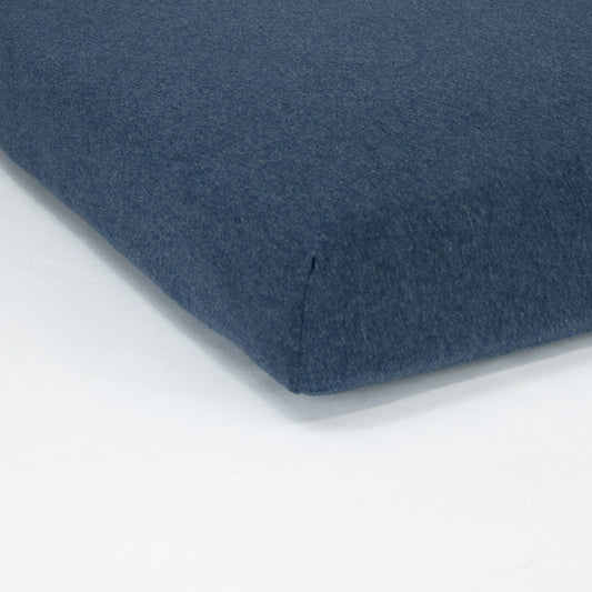 Corner of mattress with organic jersey fitted cot sheet in indigo blue