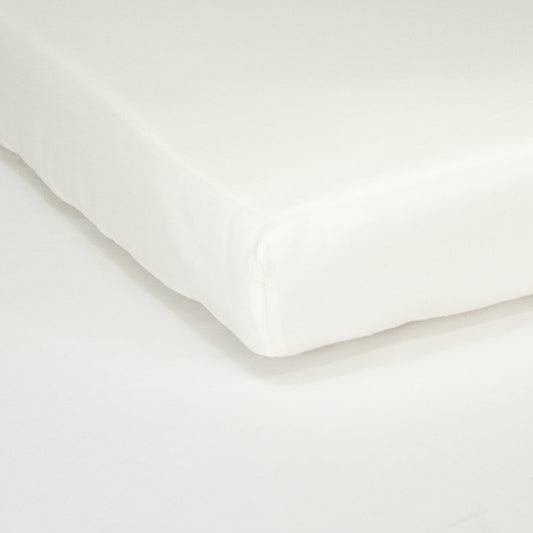 Corner of mattress with organic cotton fitted cot sheet in warm white
