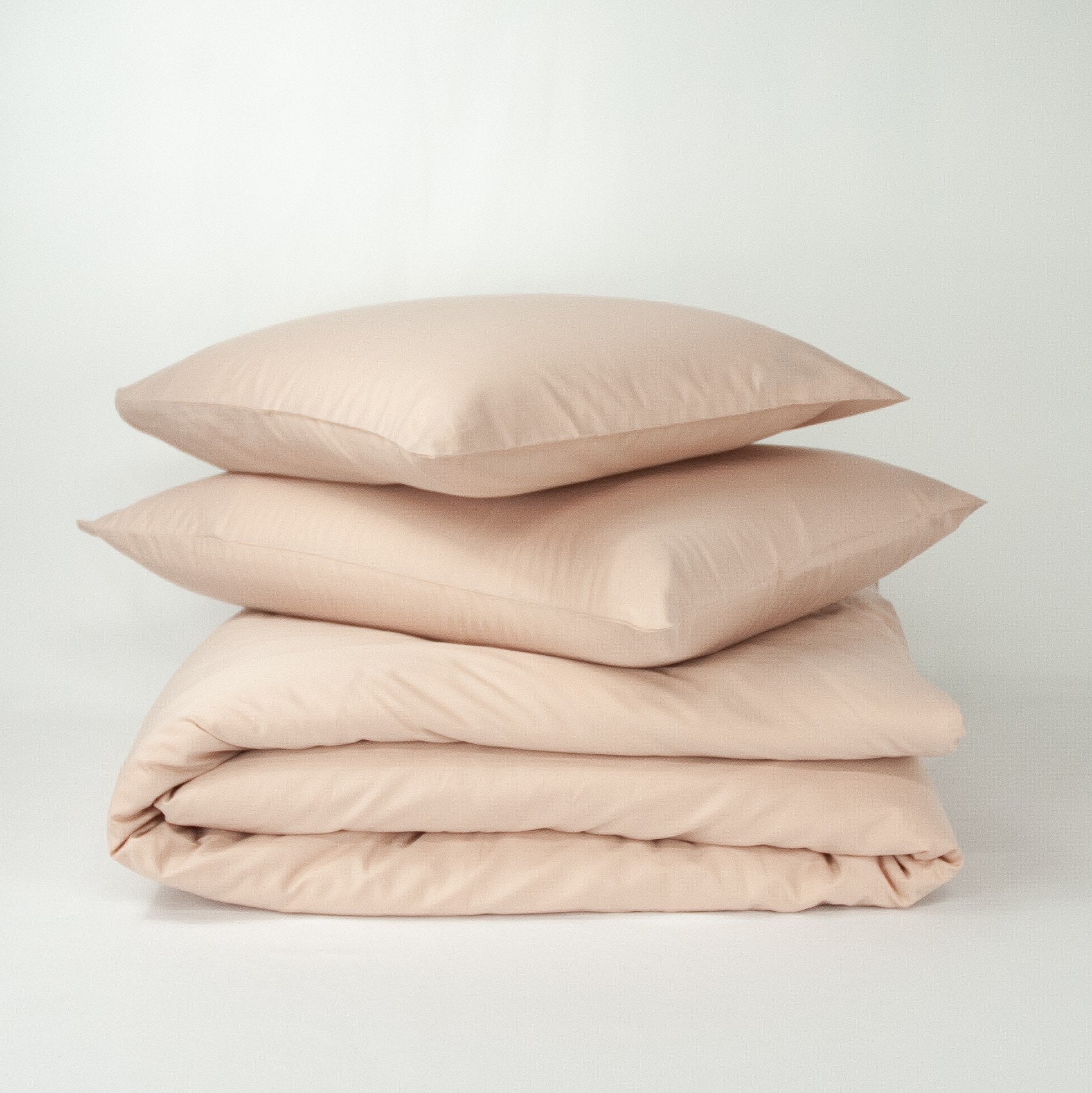 Stack of organic cotton quilt cover set with pillowcases and folded quilt cover in blush pink