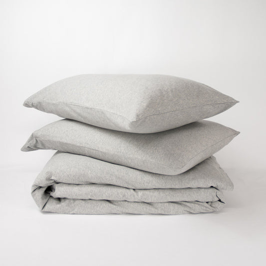 Stack of organic jersey quilt cover set with pillowcases and folded quilt cover in cloud grey
