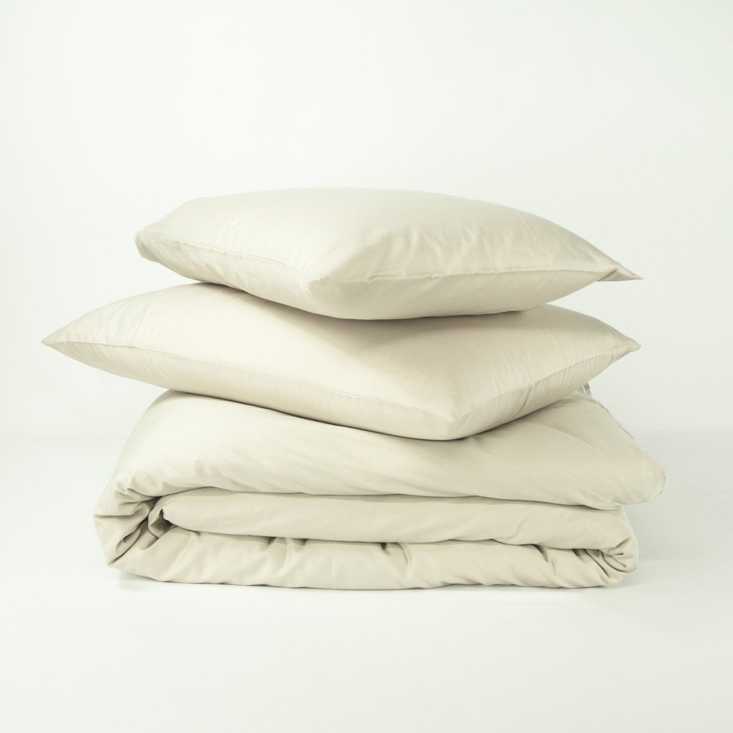 Stack of organic cotton quilt cover set with pillowcases and folded quilt cover in egg shell white