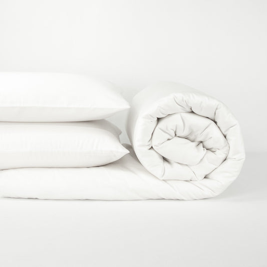 Stack of organic cotton quilt cover set with pillowcases and rolled up quilt cover in pure white