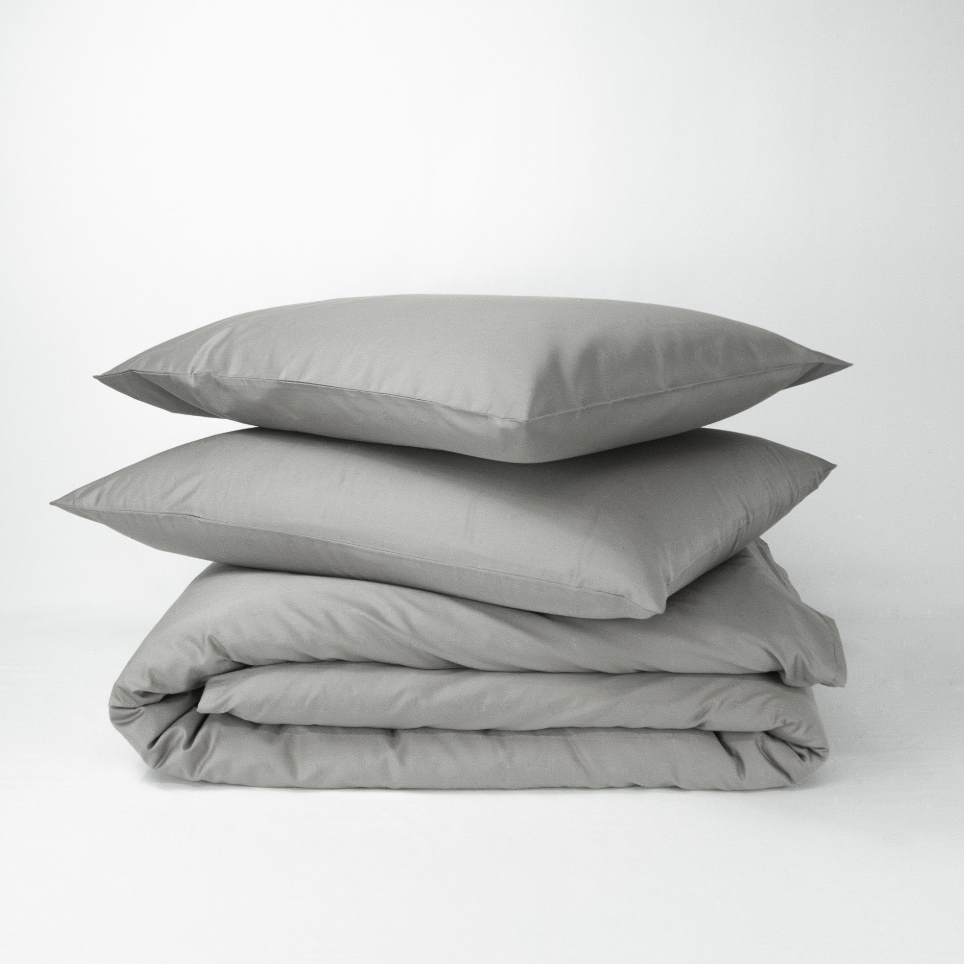 Stack of organic cotton quilt cover set with pillowcases and folded quilt cover in sleet grey