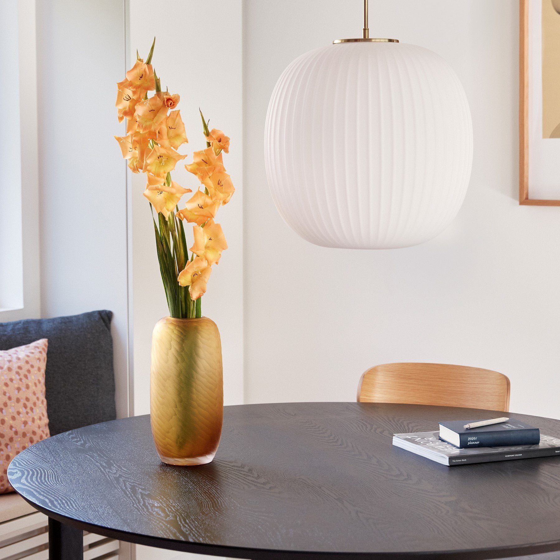 Hubsch Interior Scandi style tall dune textured vase in amber gold glass on a black wood dining table with flower arrangement