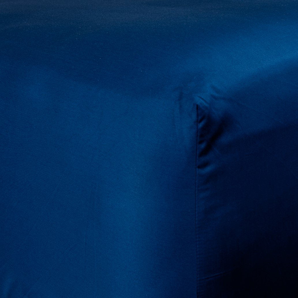 Corner of bed with organic cotton fitted sheet in classic blue