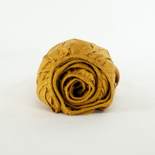 Rolled up organic cotton fitted sheet in honey gold