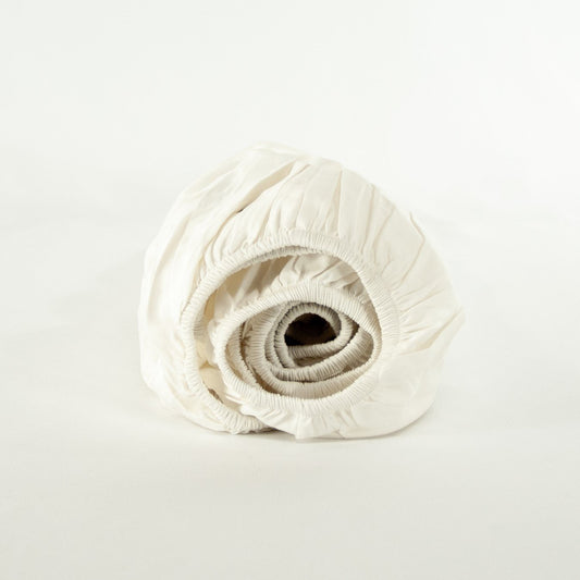 Rolled up organic cotton fitted sheet in warm white