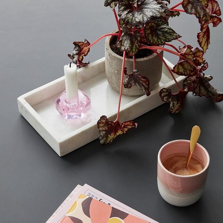 Hubsch Interior modern candle holder in pink glass, on a white marble tray with plant and cup of coffee