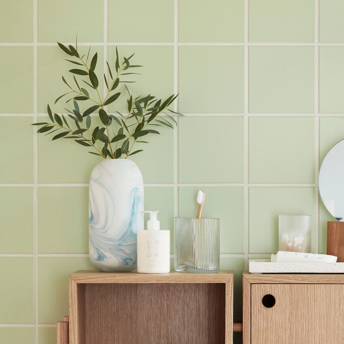 Hubsch Interior Scandi style marbled vases in white and blue glass sitting on bathroom bench with green tile wall