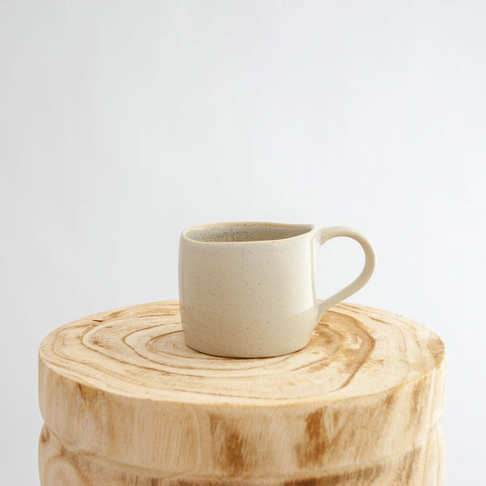 Robert Gordon oatmeal cream organic mug coffee cup sitting on a natural wooden round side table