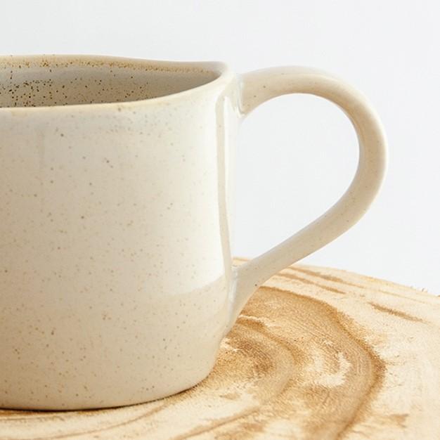 Close up of a Robert Gordon oatmeal cream organic mug coffee cup sitting on a natural wooden round side table