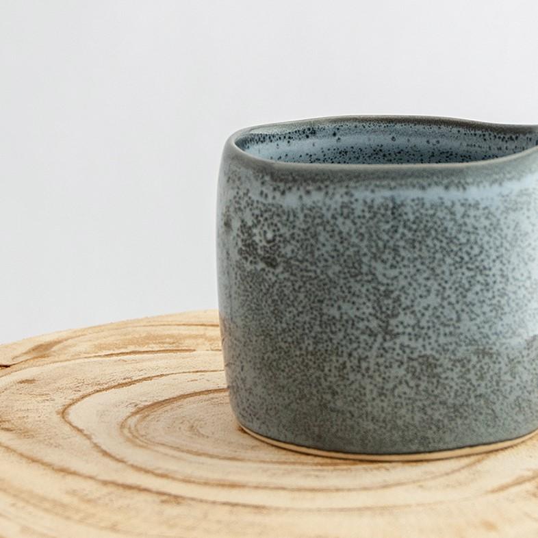 Close up of a Robert Gordon storm grey organic mug coffee cup sitting on a natural wooden round side table