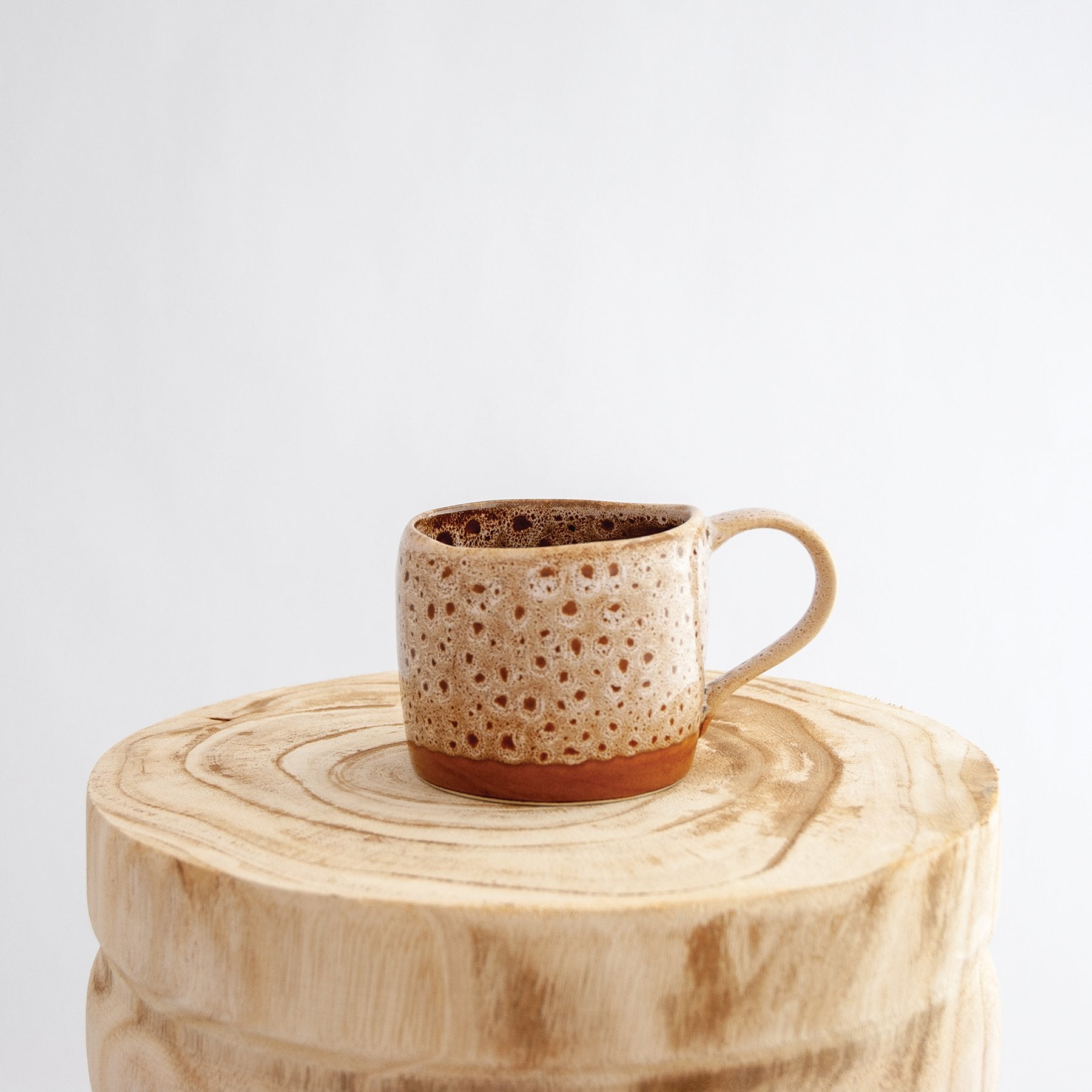 Robert Gordon white ochre organic mug coffee cup sitting on a natural wooden round side table