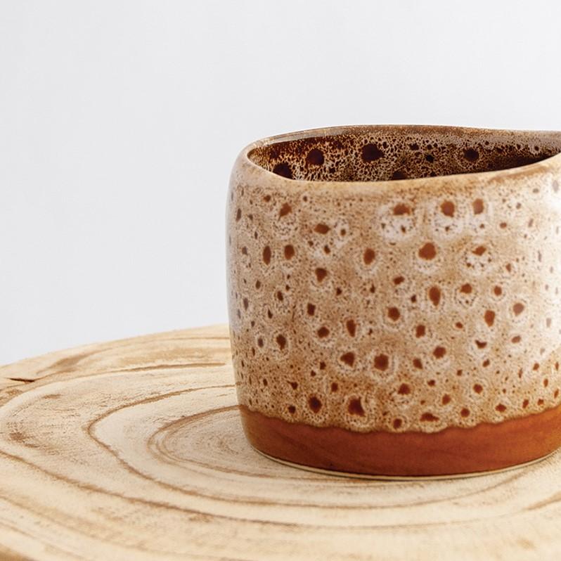 Close up of a Robert Gordon white ochre organic mug coffee cup sitting on a natural wooden round side table