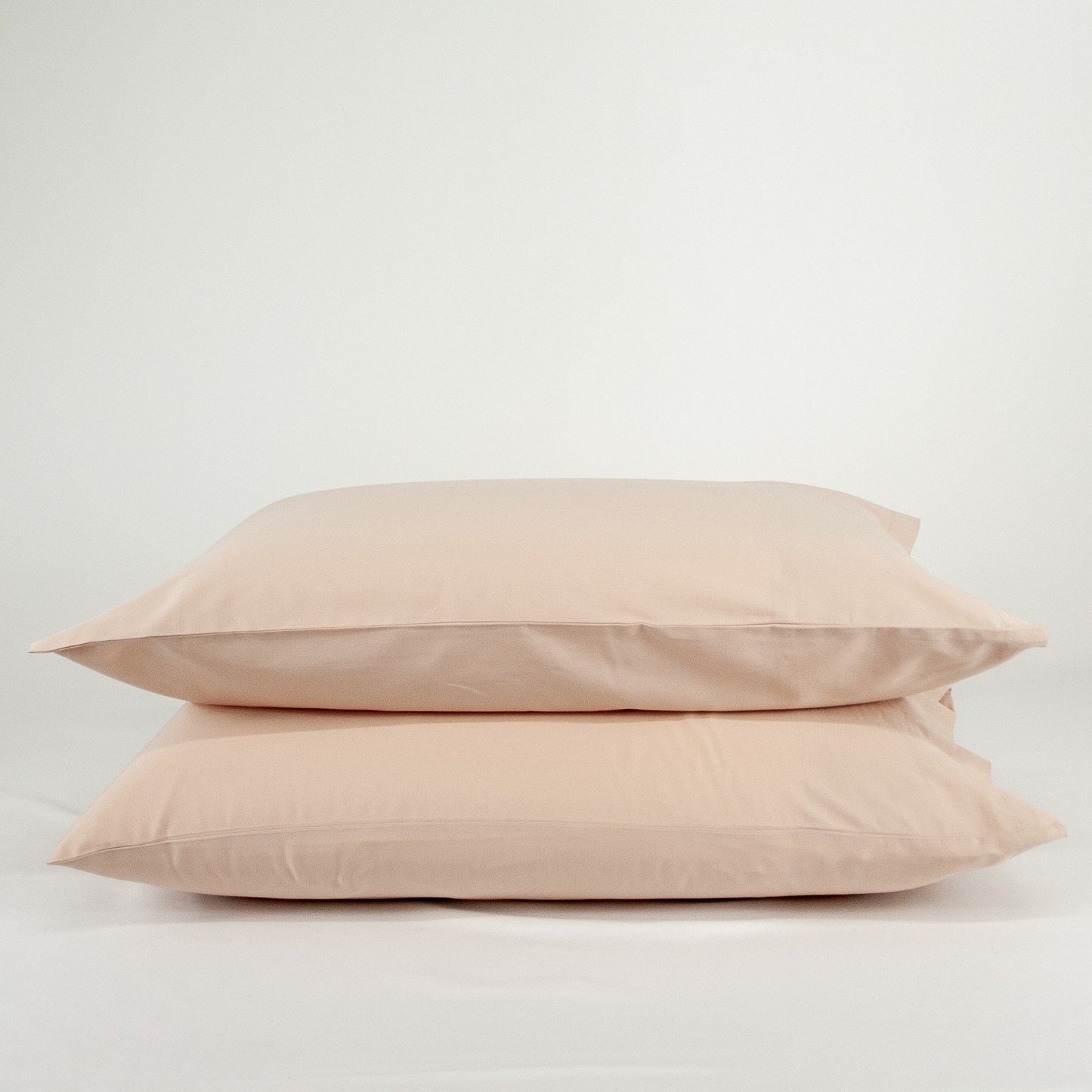 Stacked organic cotton pillowcases in blush pink