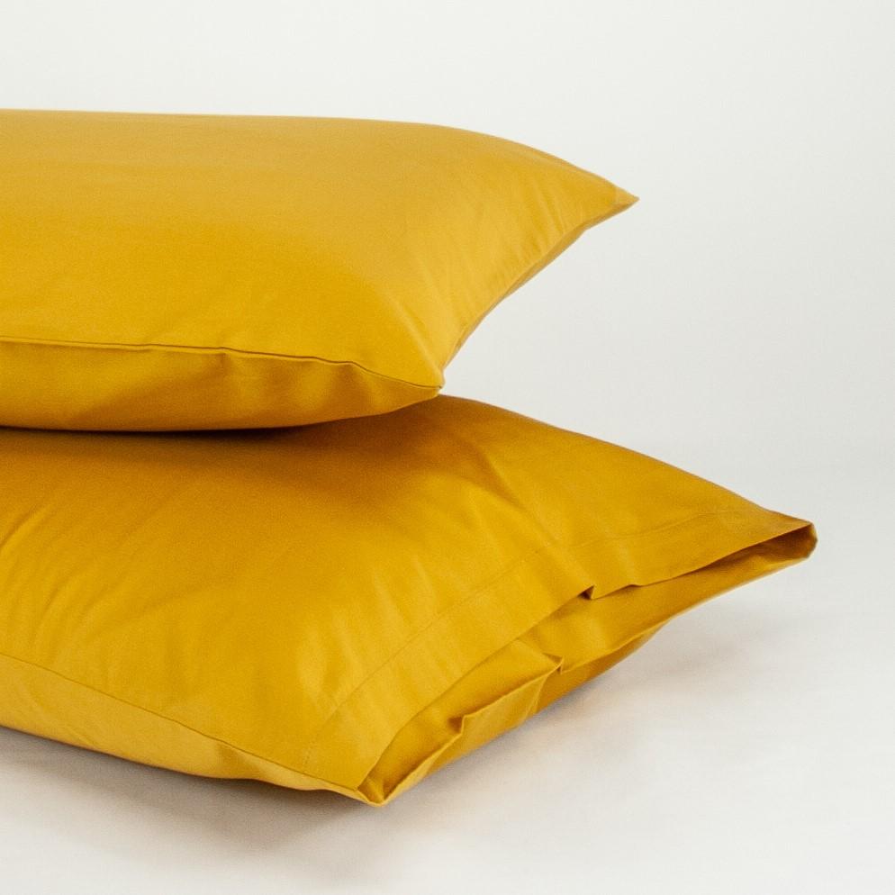 Stacked organic cotton pillowcases in honey gold