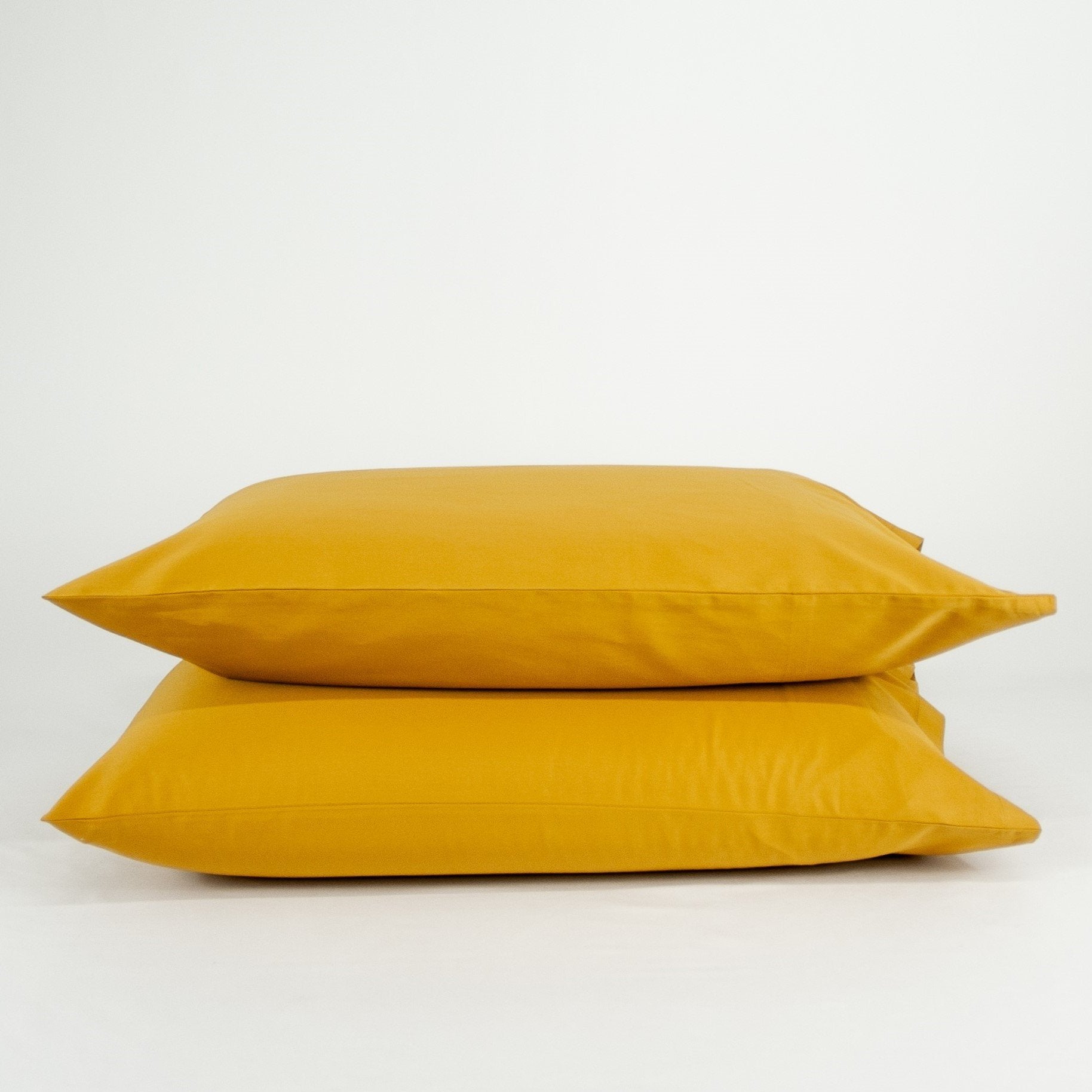 Stacked organic cotton pillowcases in honey gold
