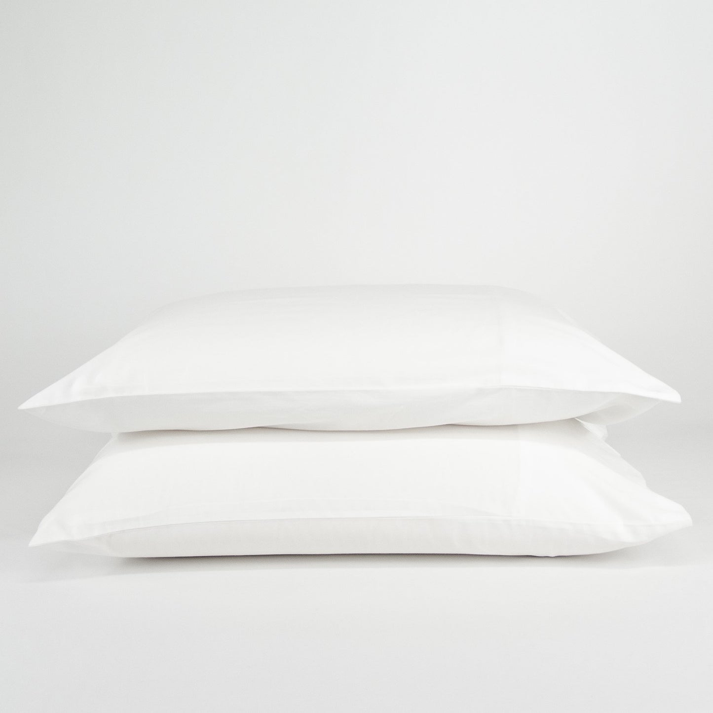Stacked organic cotton pillowcases in pure white