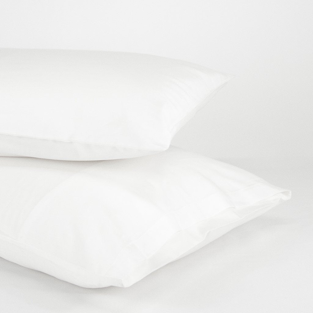 Stacked organic cotton pillowcases in pure white