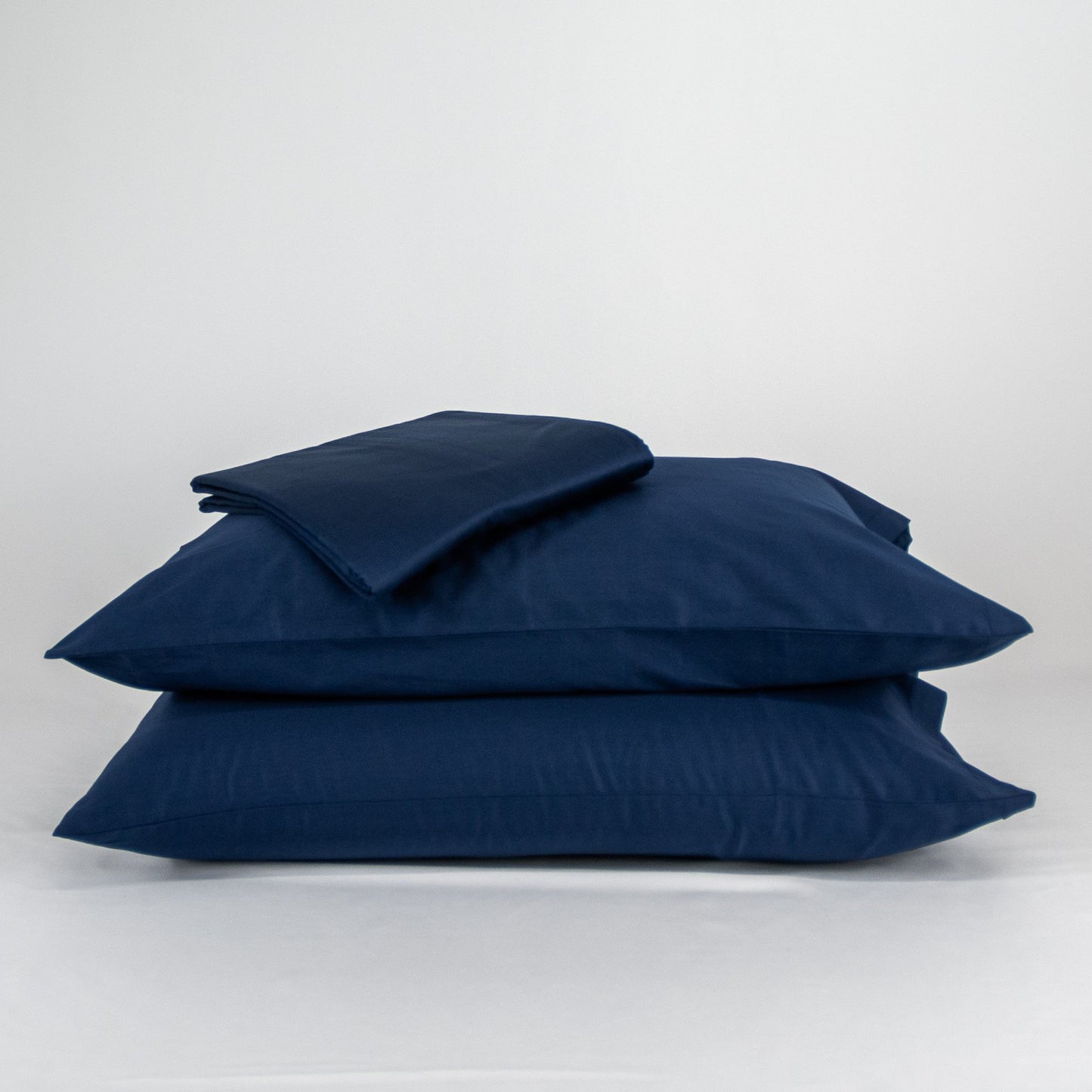 Stacked organic cotton pillowcases and sheets in classic blue
