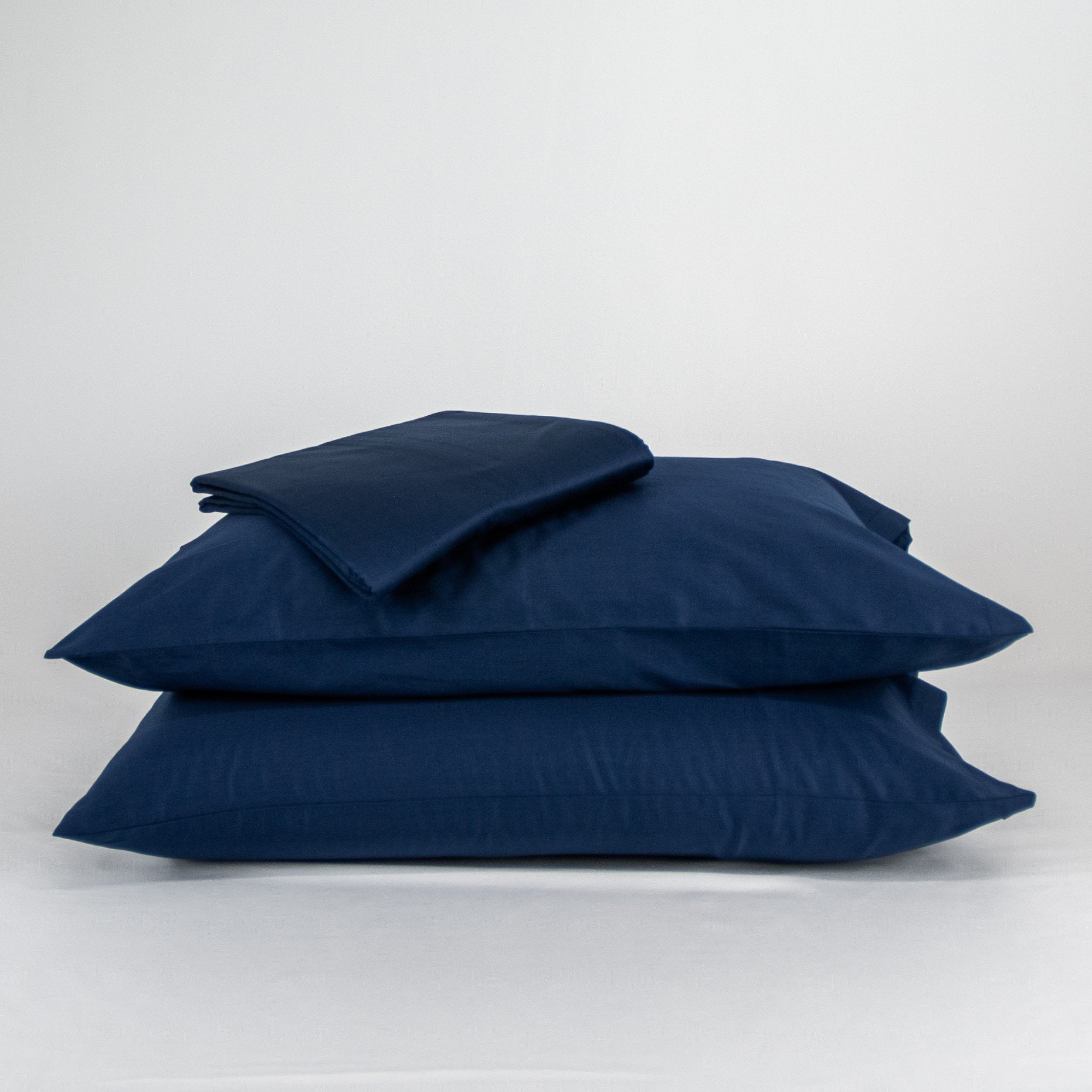 Stacked organic cotton pillowcases and sheets in classic blue