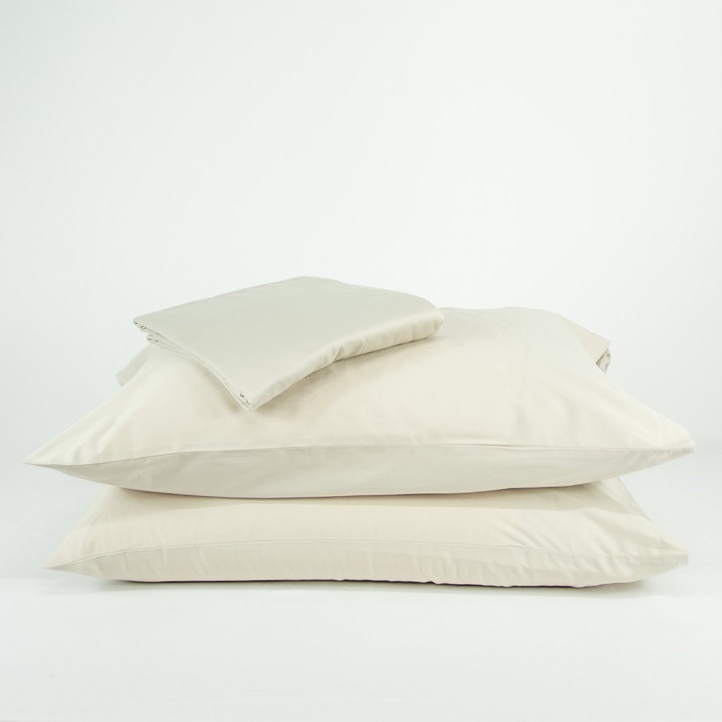 Stacked organic cotton pillowcases and sheets in egg shell white
