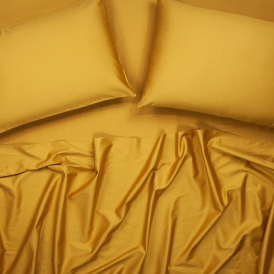 Birds eye view of organic cotton bed sheets with pillowcases in honey gold
