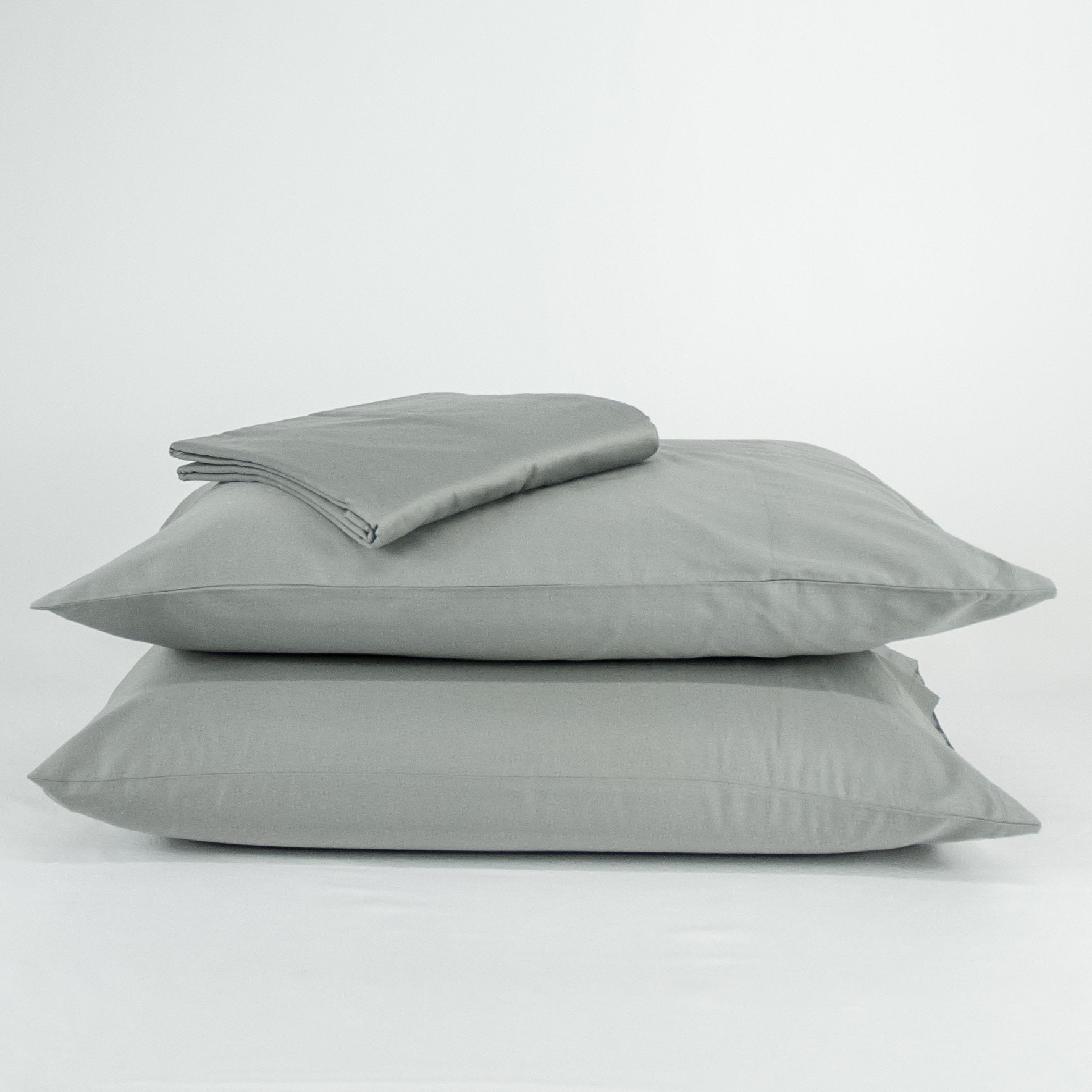 Stacked organic cotton pillowcases and sheets in sleet grey