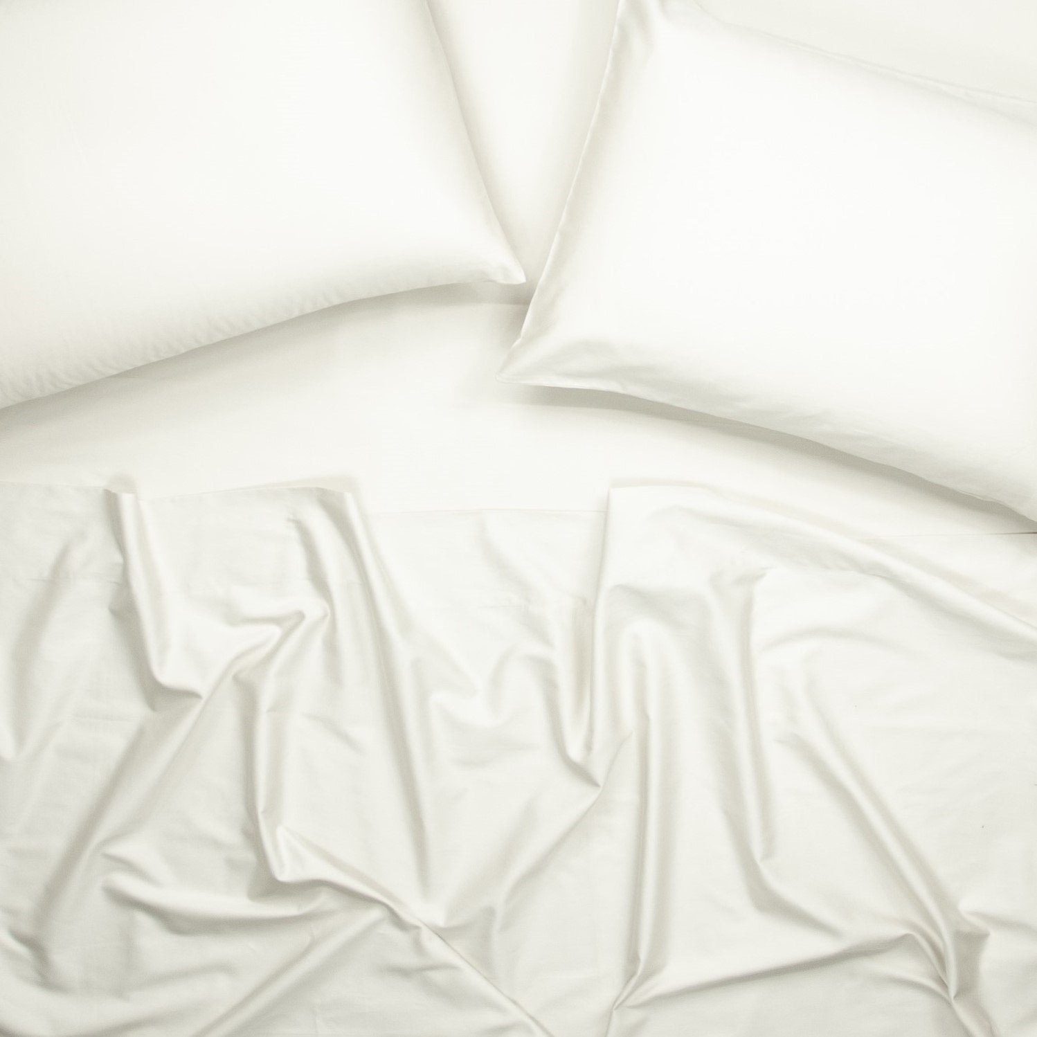 Birds eye view of organic cotton bed sheets with pillowcases in warm white