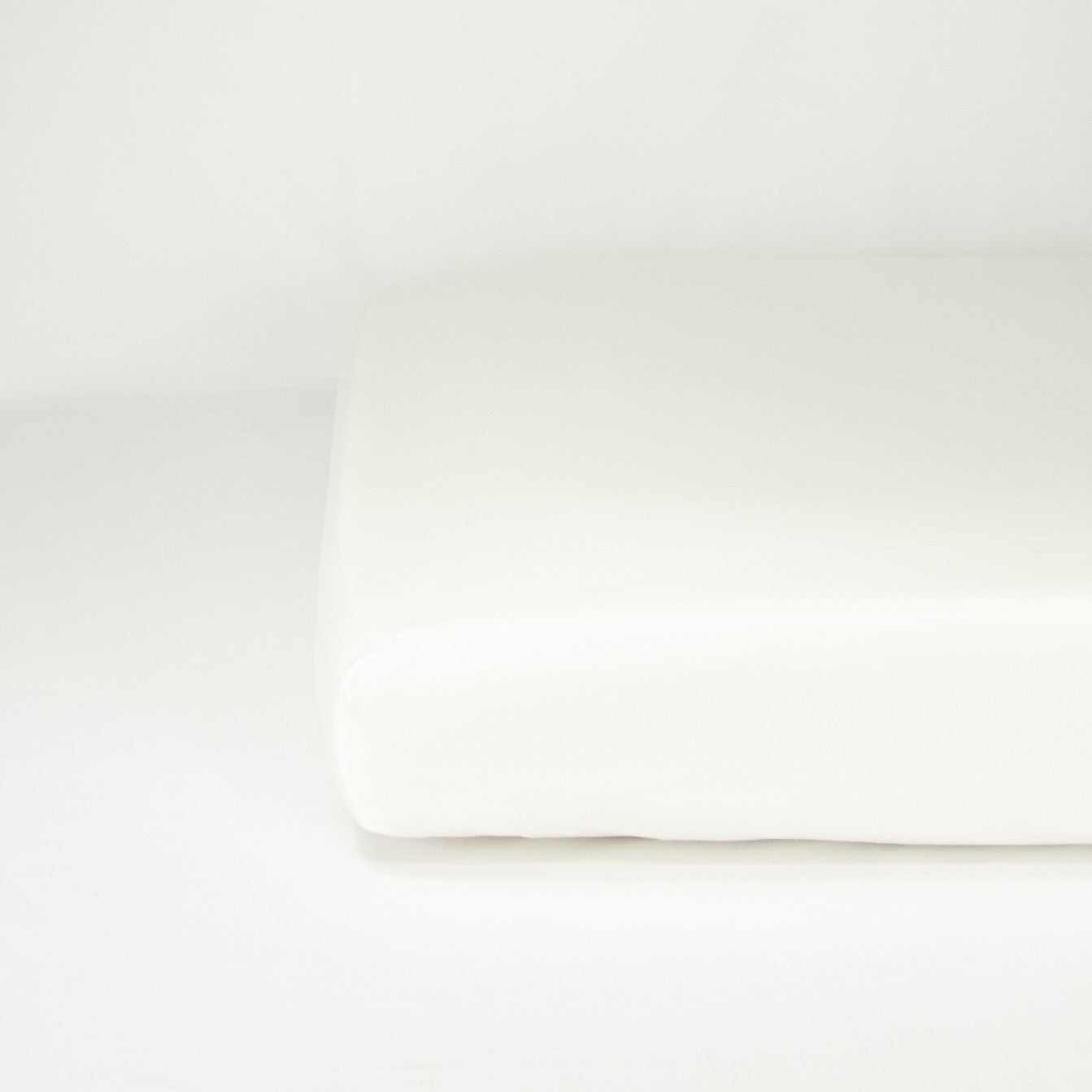 End of mattress with organic cotton fitted cot sheet in warm white