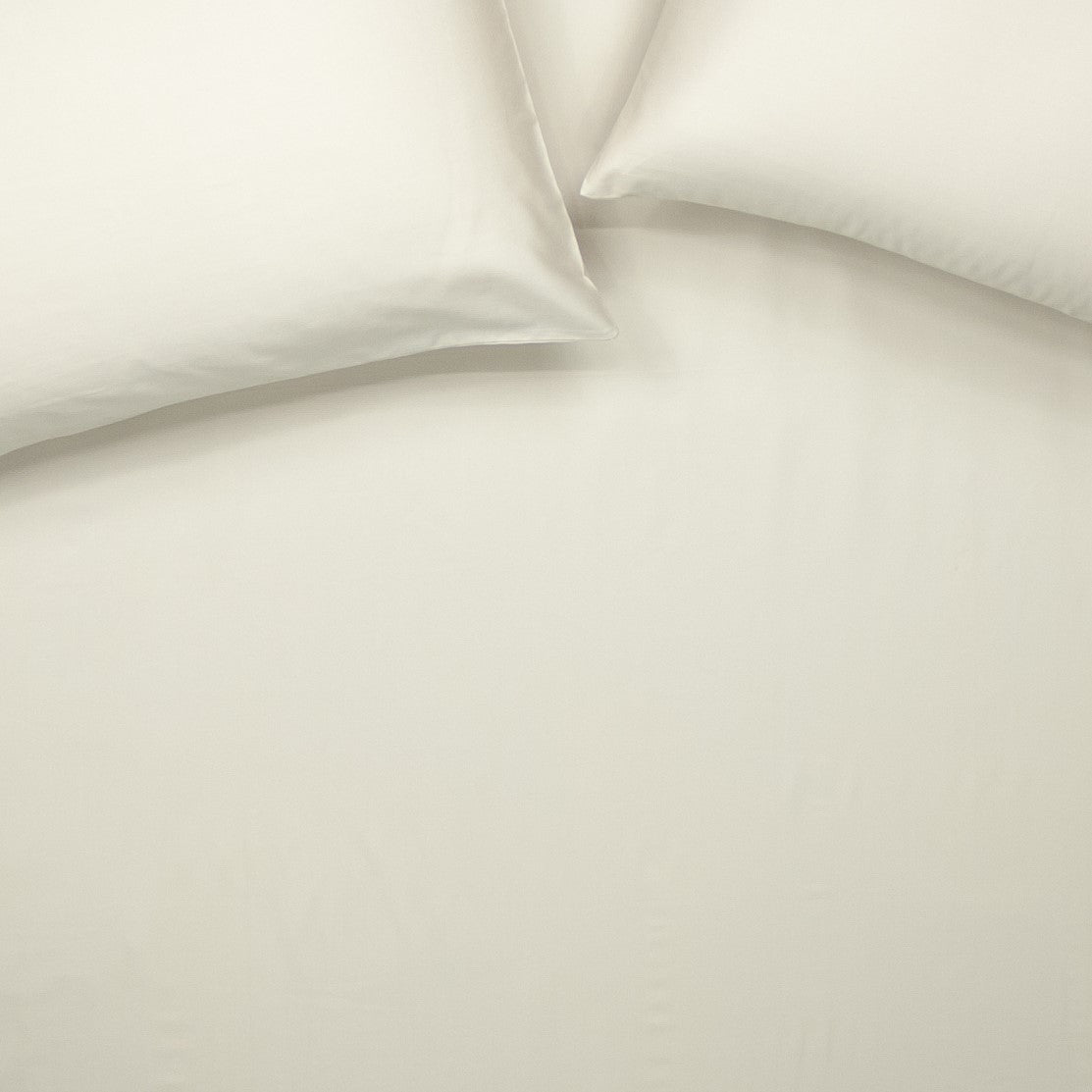 Birds eye view of organic cotton fitted sheet with pillowcases in egg shell white