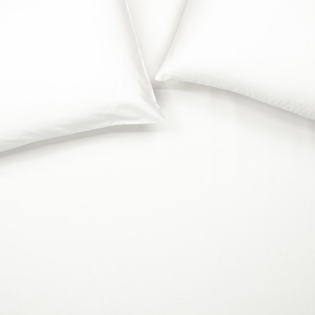 Birds eye view of organic cotton fitted sheet with pillowcases in pure white