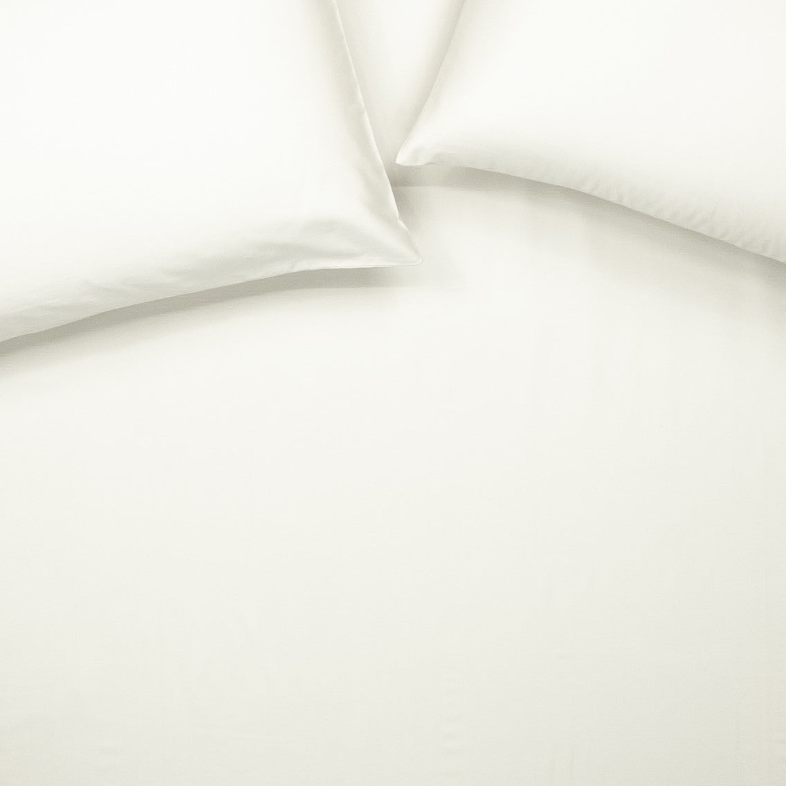 Birds eye view of organic cotton fitted sheet with pillowcases in warm white