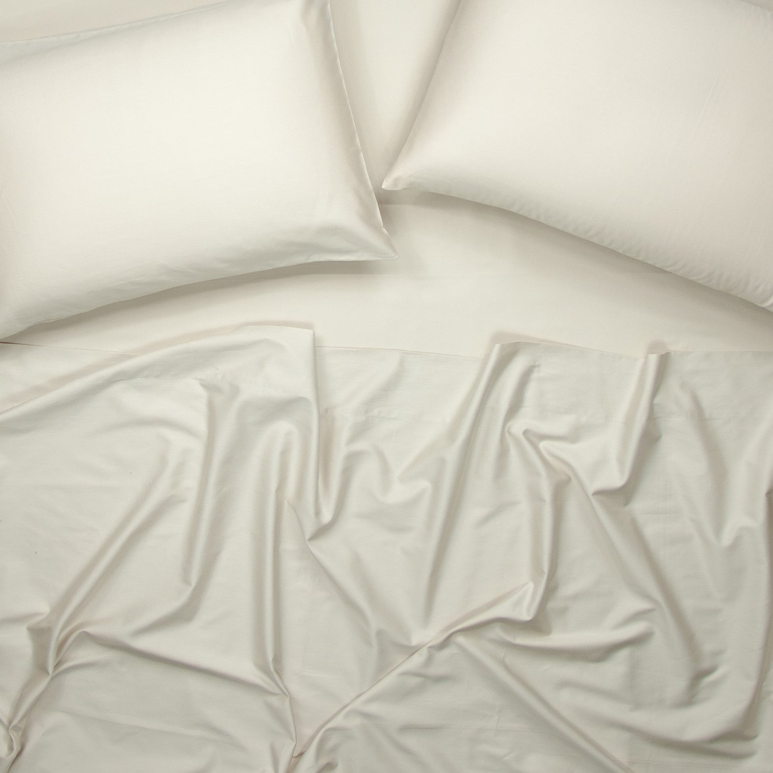 Birds eye view of organic cotton bed sheets with pillowcases in egg shell white